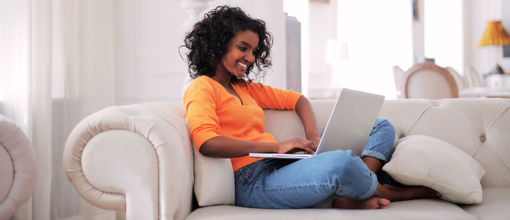 Woman with computer on couch.